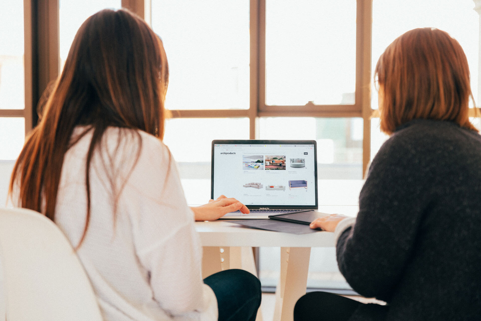 two women talkling while looking at laptop computer